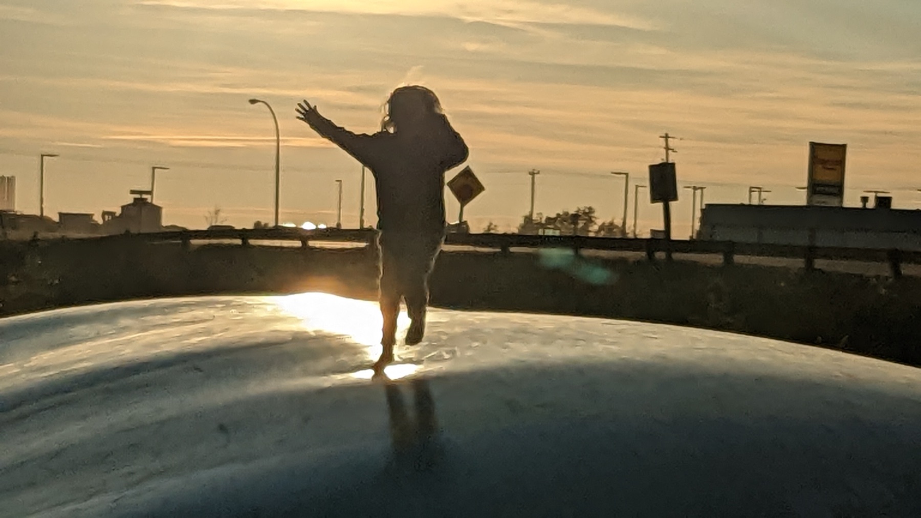 A kid mid-jump, silhouetted against a prairie sunset
